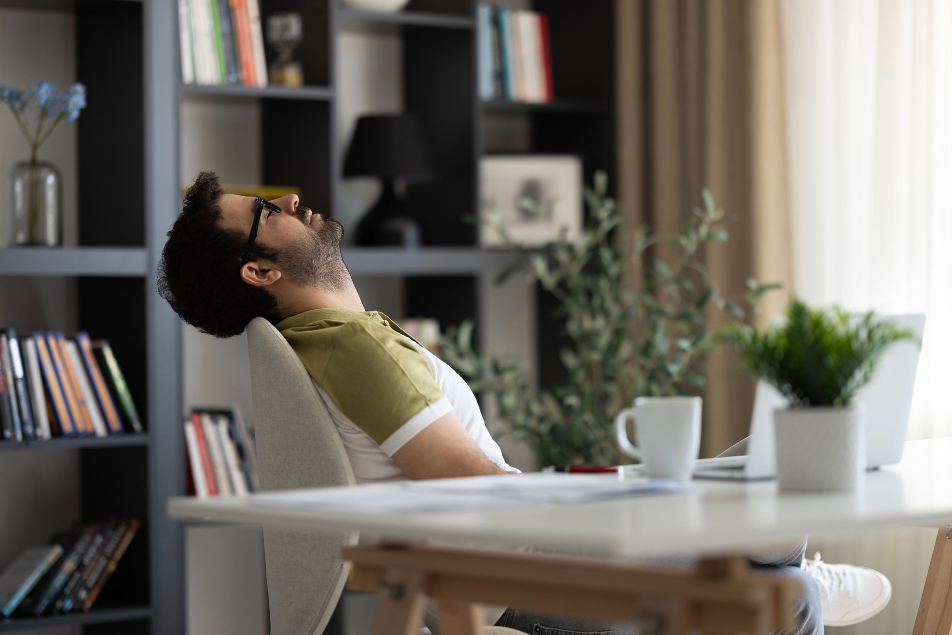 Taking break. Smiling middle aged man relaxing on chair, sitting at table and resting, using pc laptop at office